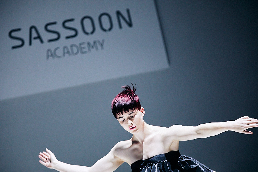 Model with arms out to the side on stage at Vidal Sassoon hair show.